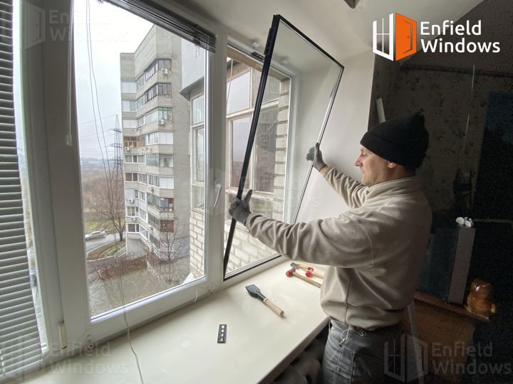 майстер ремонтує пластикове вікно